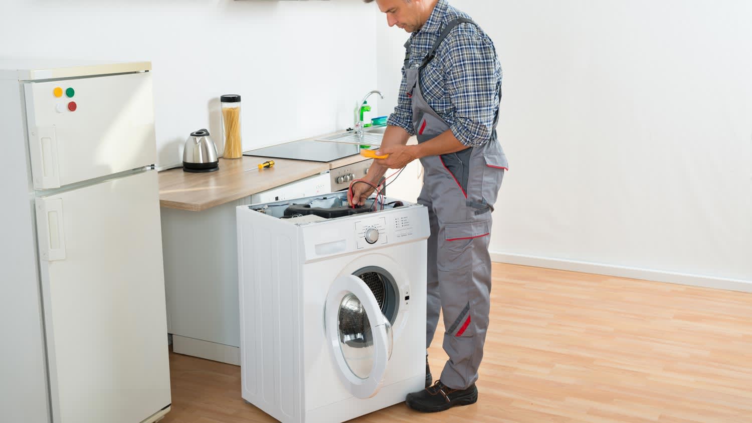 An electrician checking a washing machine with a multimeter