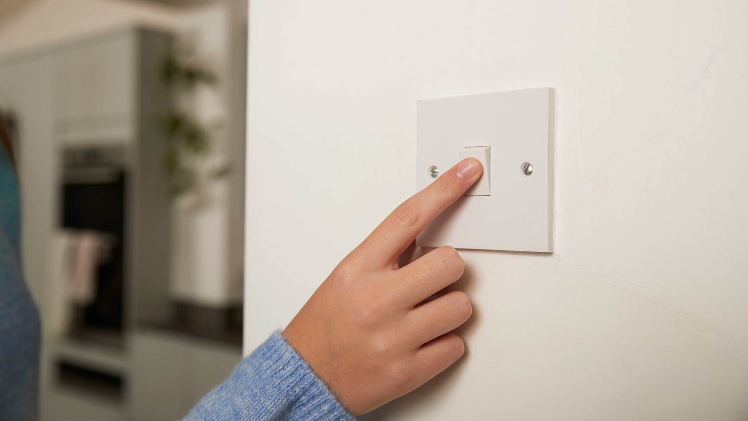 A woman turning on a light switch