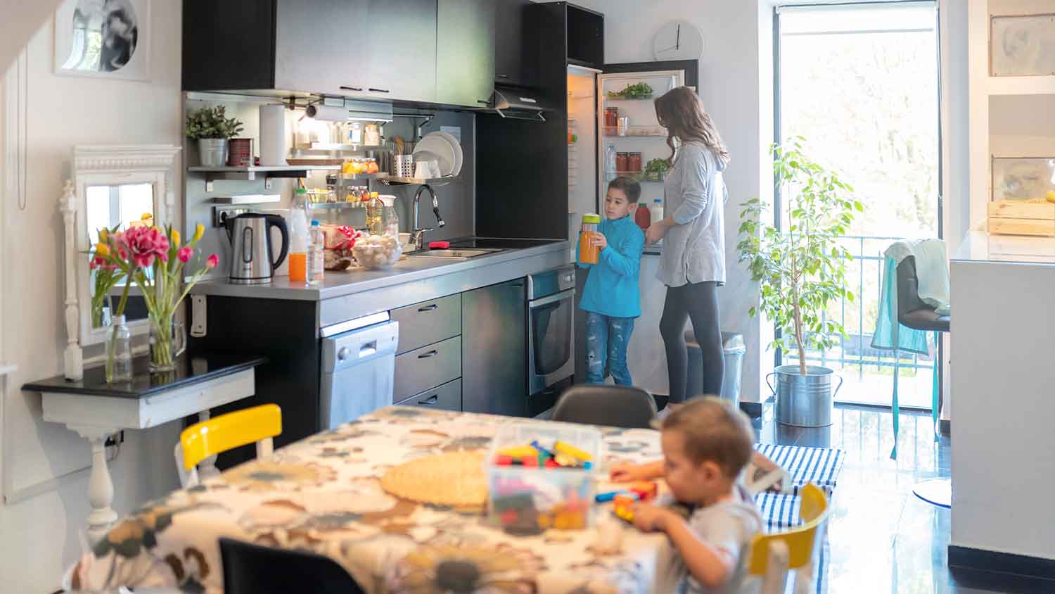 Boy taking orange juice from the fridge in the kitchen