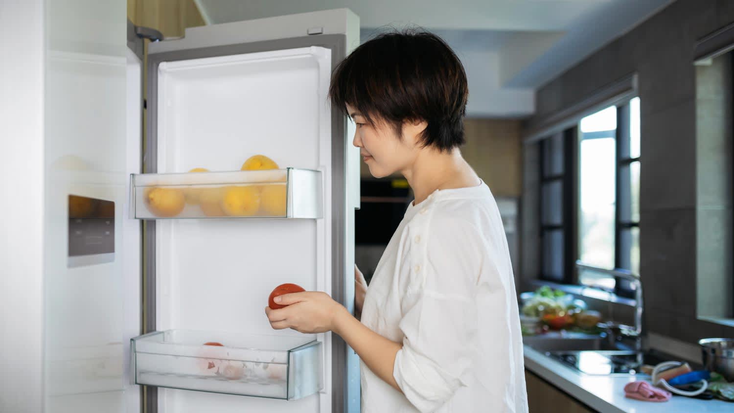 A woman picking fruit from the refrigerator