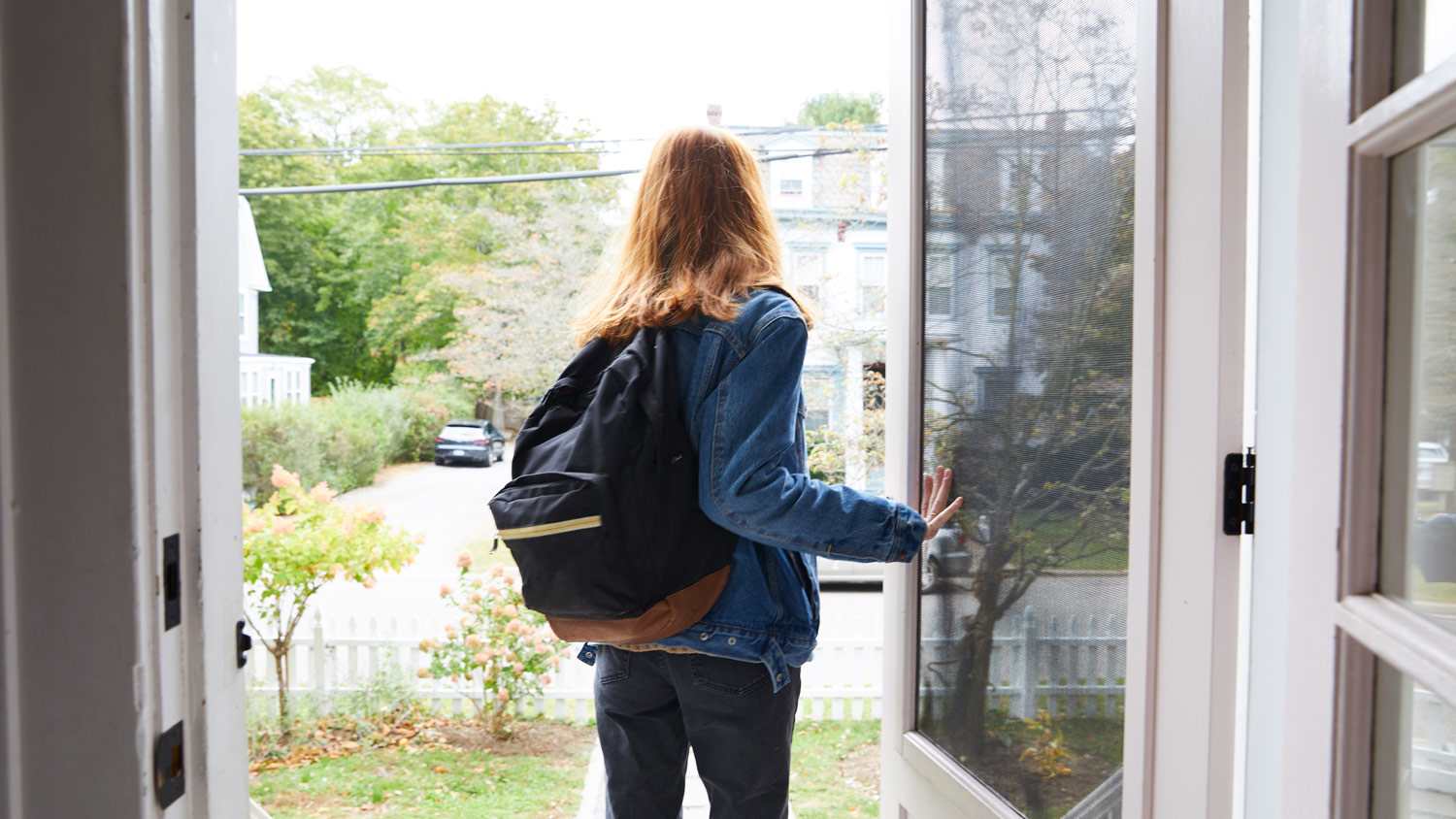 Teenage girl walking out the front door of her house
