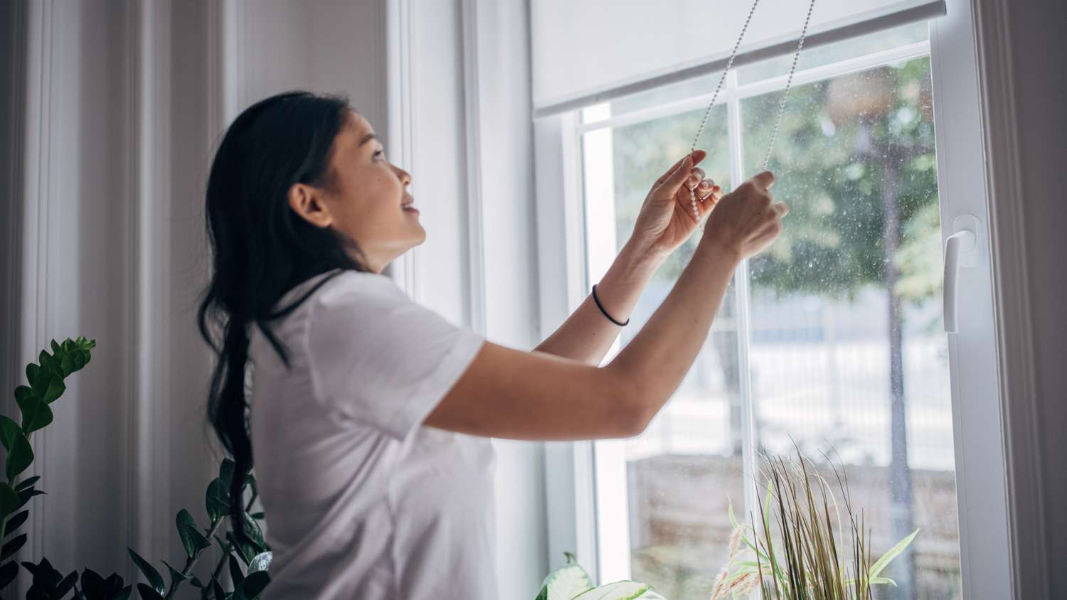 Woman lowering blinds on window