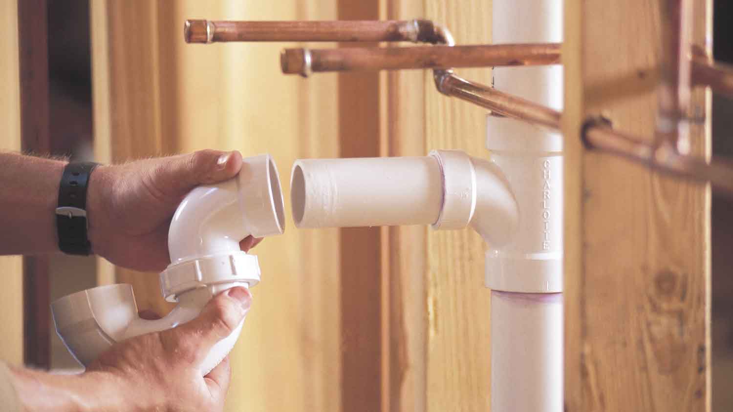 Plumber installing pvc pipes in a new house construction