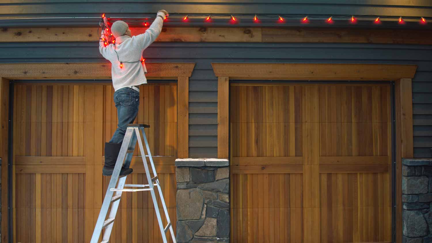 A man hanging a Christmas string of lights