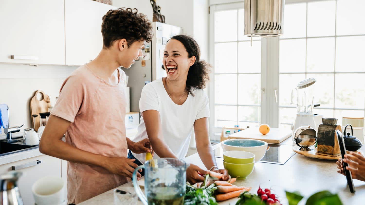 A mother laughing while preparing lunch with her son