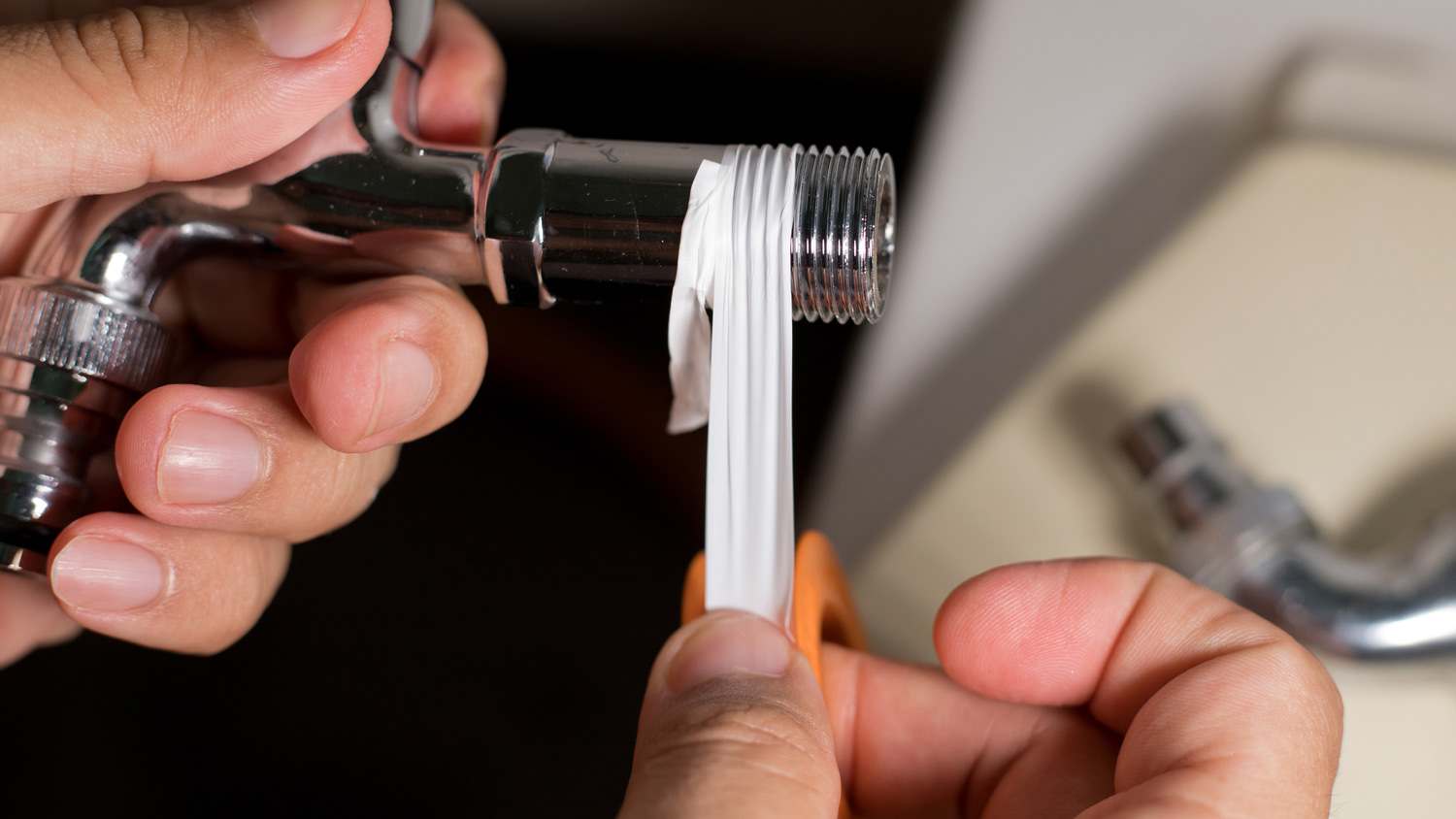Applying white tape to pipe.