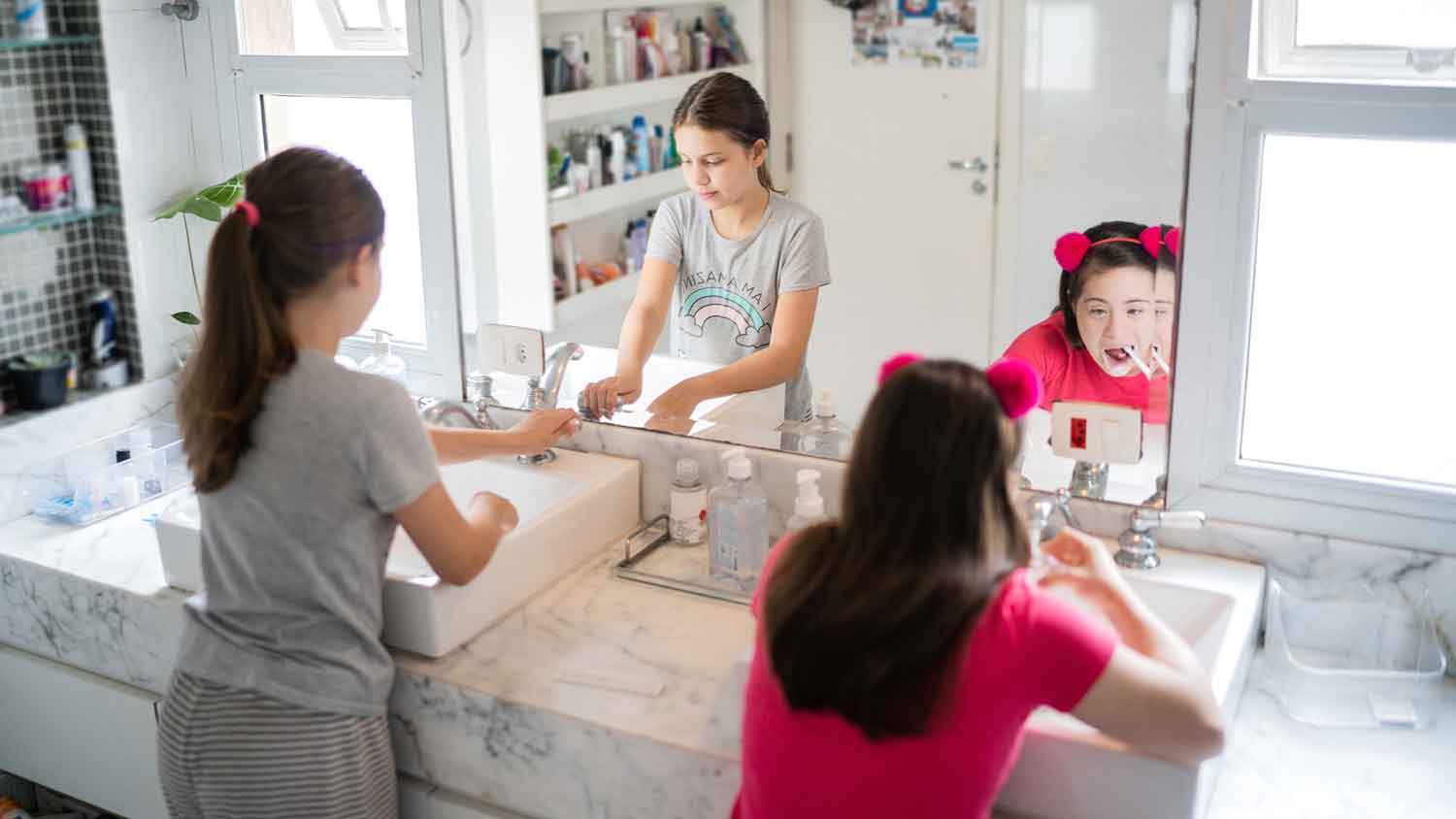 Sisters at home brushing teeth together