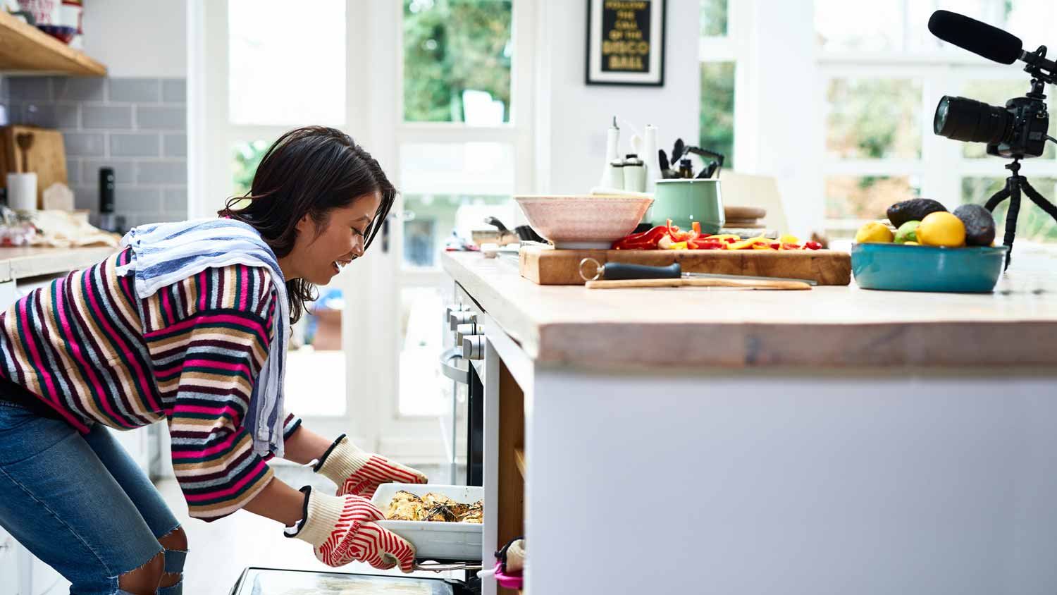 A woman taking a baked meal out of the oven