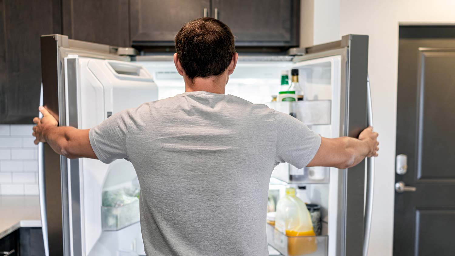 A man opening a double door refrigerator