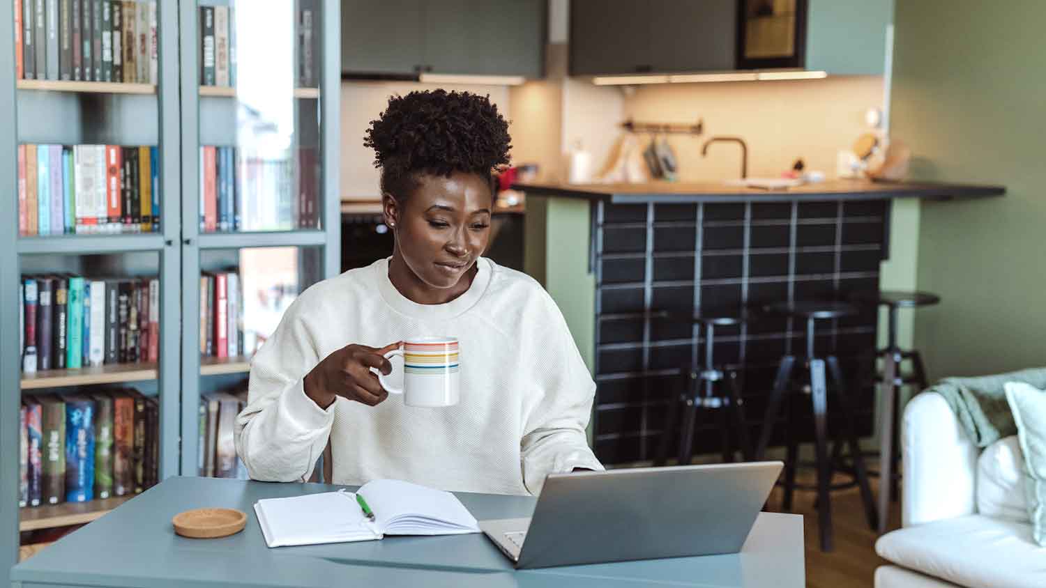 Woman at home working on laptop and drinking coffee