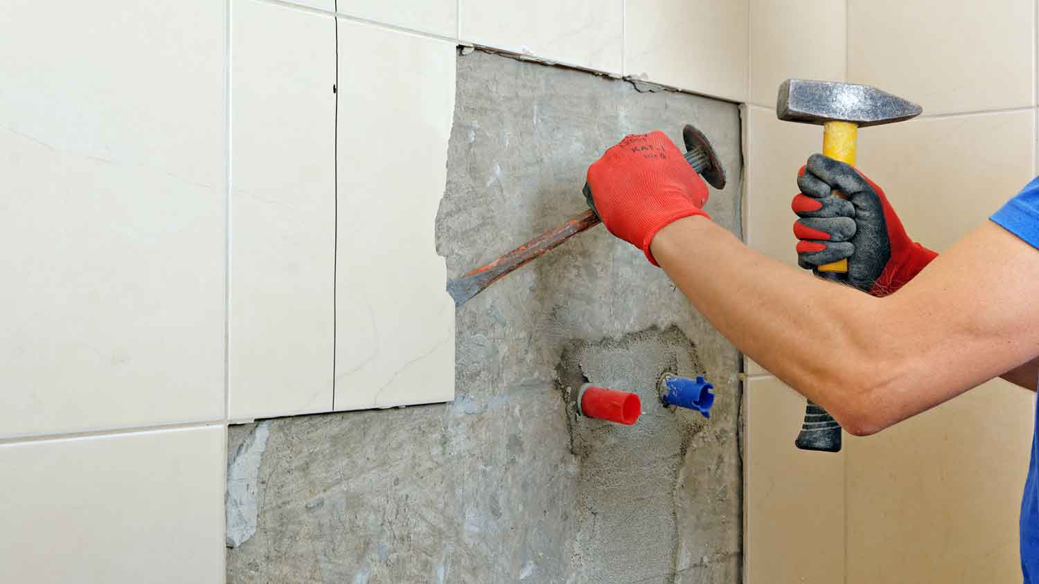 Worker using hammer and chisel to remove tiles
