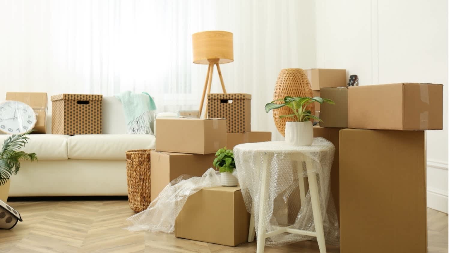 A living room with couch, moving boxes, and packing materials