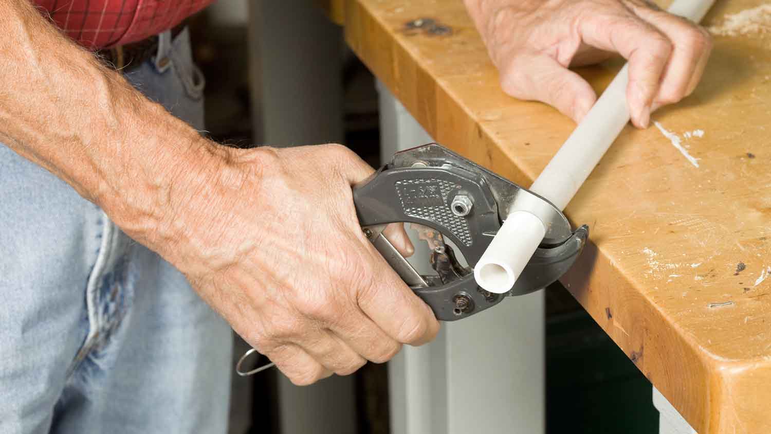Plumber using tool to cut pex pipe