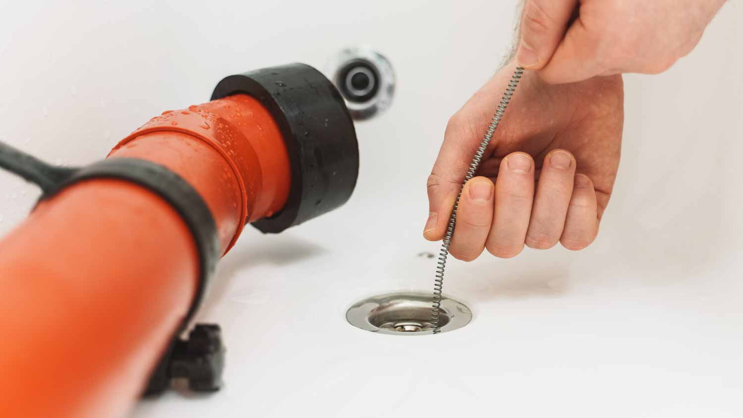 Plumber using drain snake