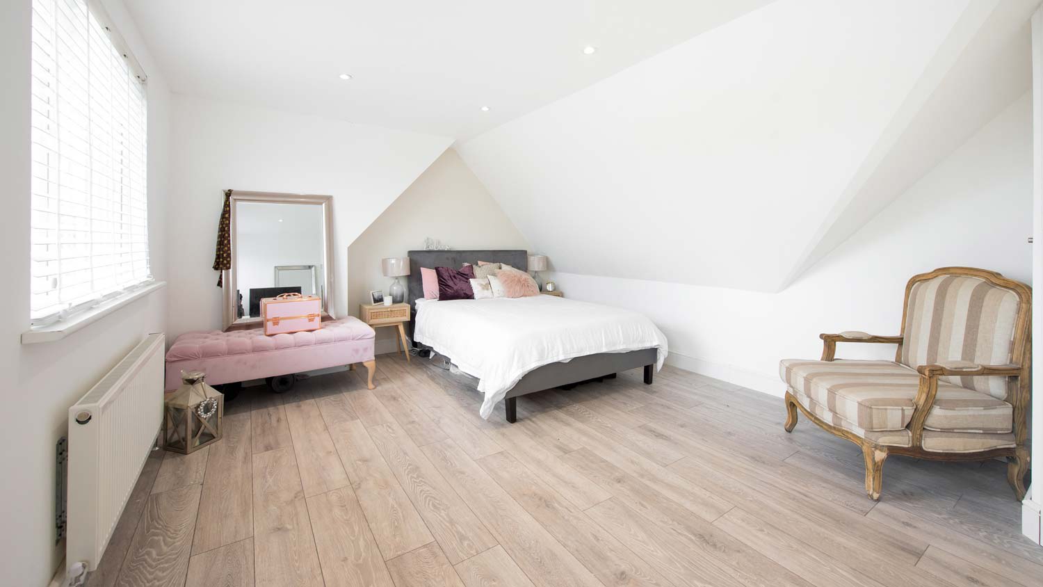 A bedroom with laminate flooring and various furniture