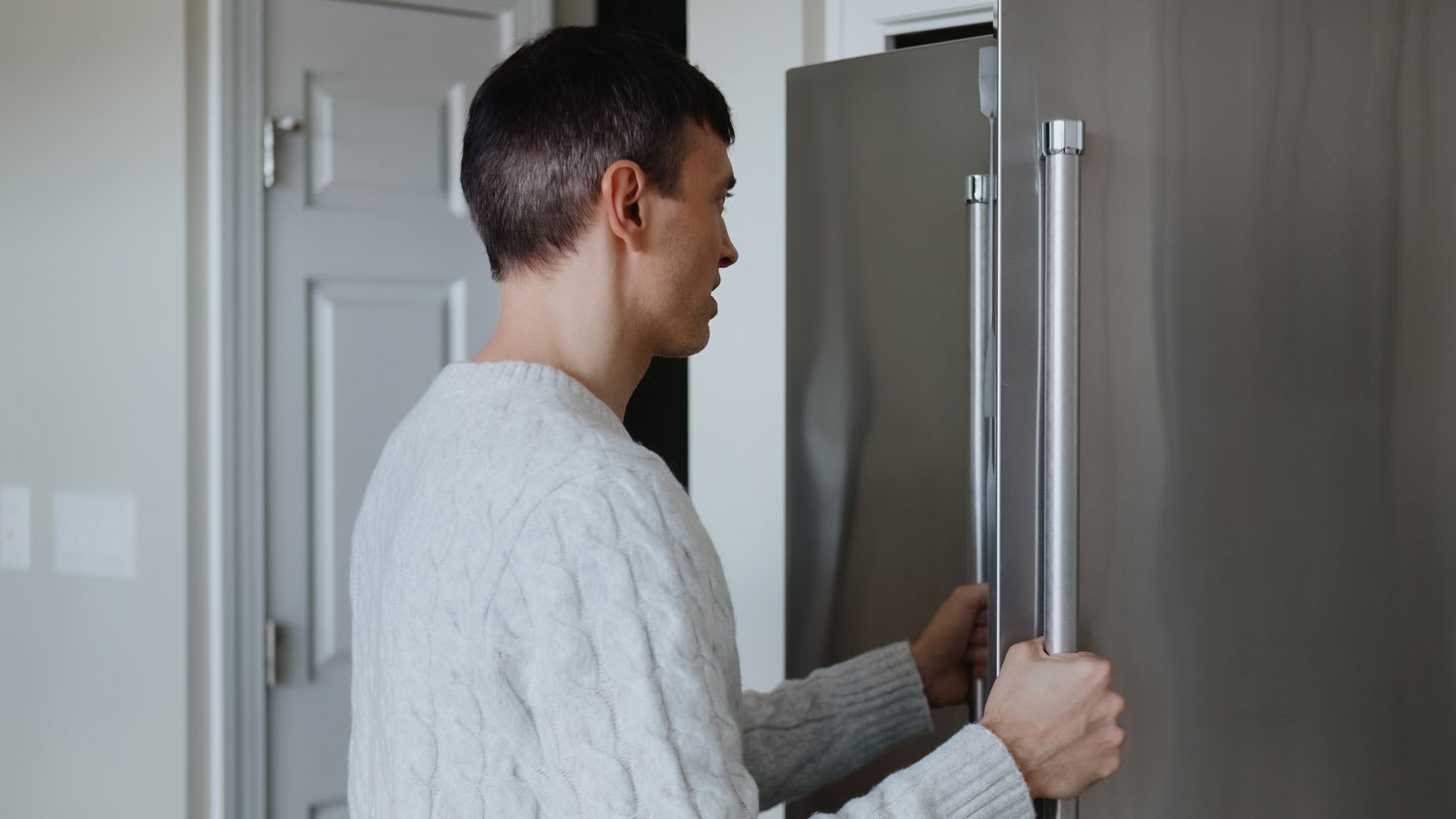 A man checking the refrigerator doors