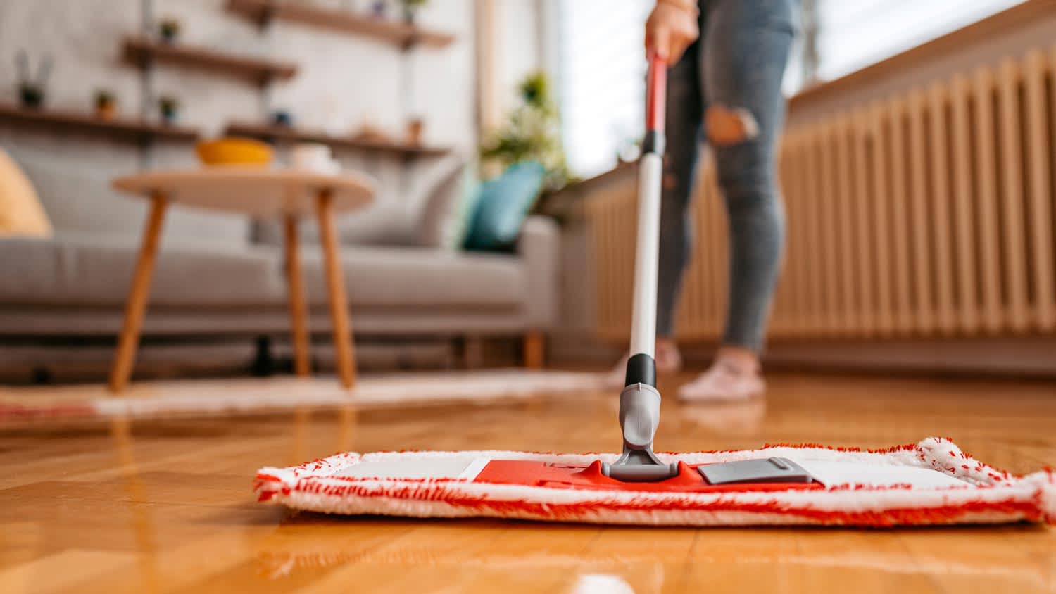 A woman cleaning laminate floor with a microfiber mop