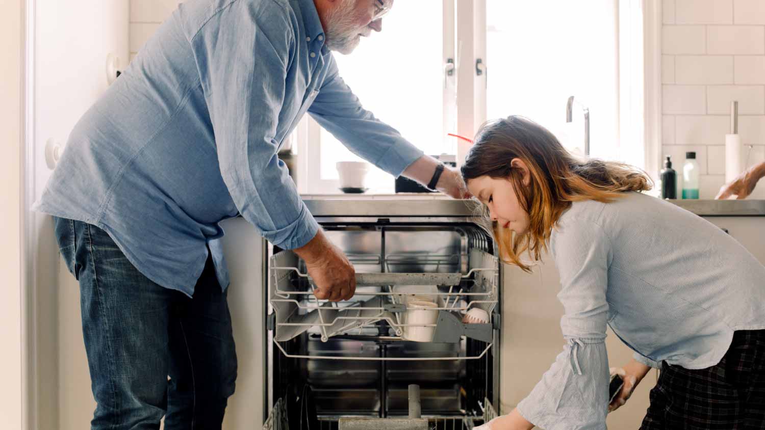 Grandfather and granddaughter cleaning dishwasher