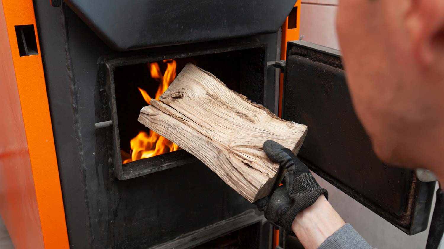 A man putting logs in a wooden furnace