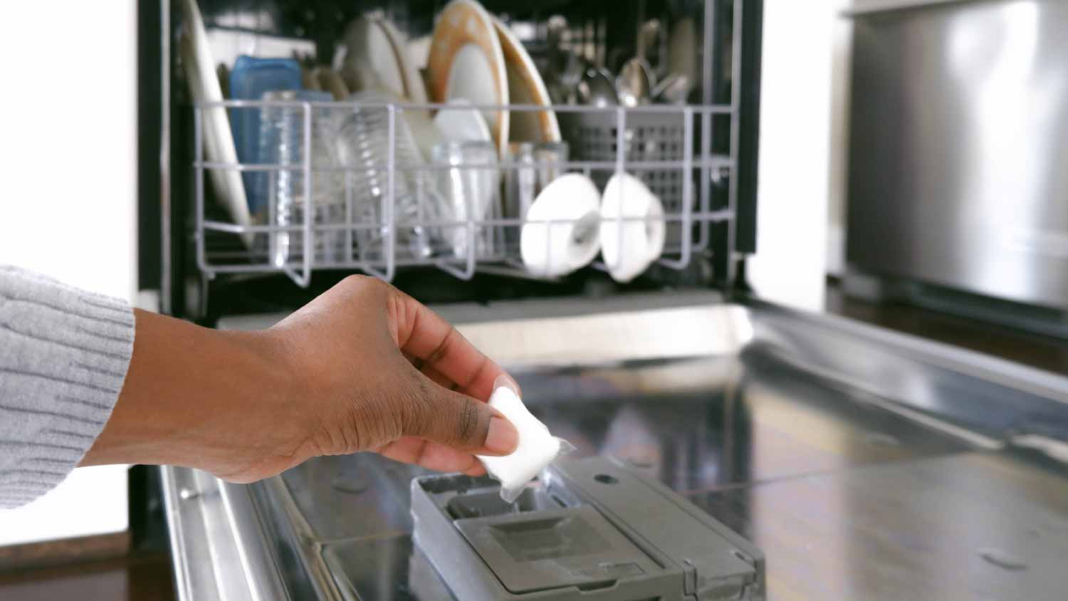 Woman putting dishwasher detergent