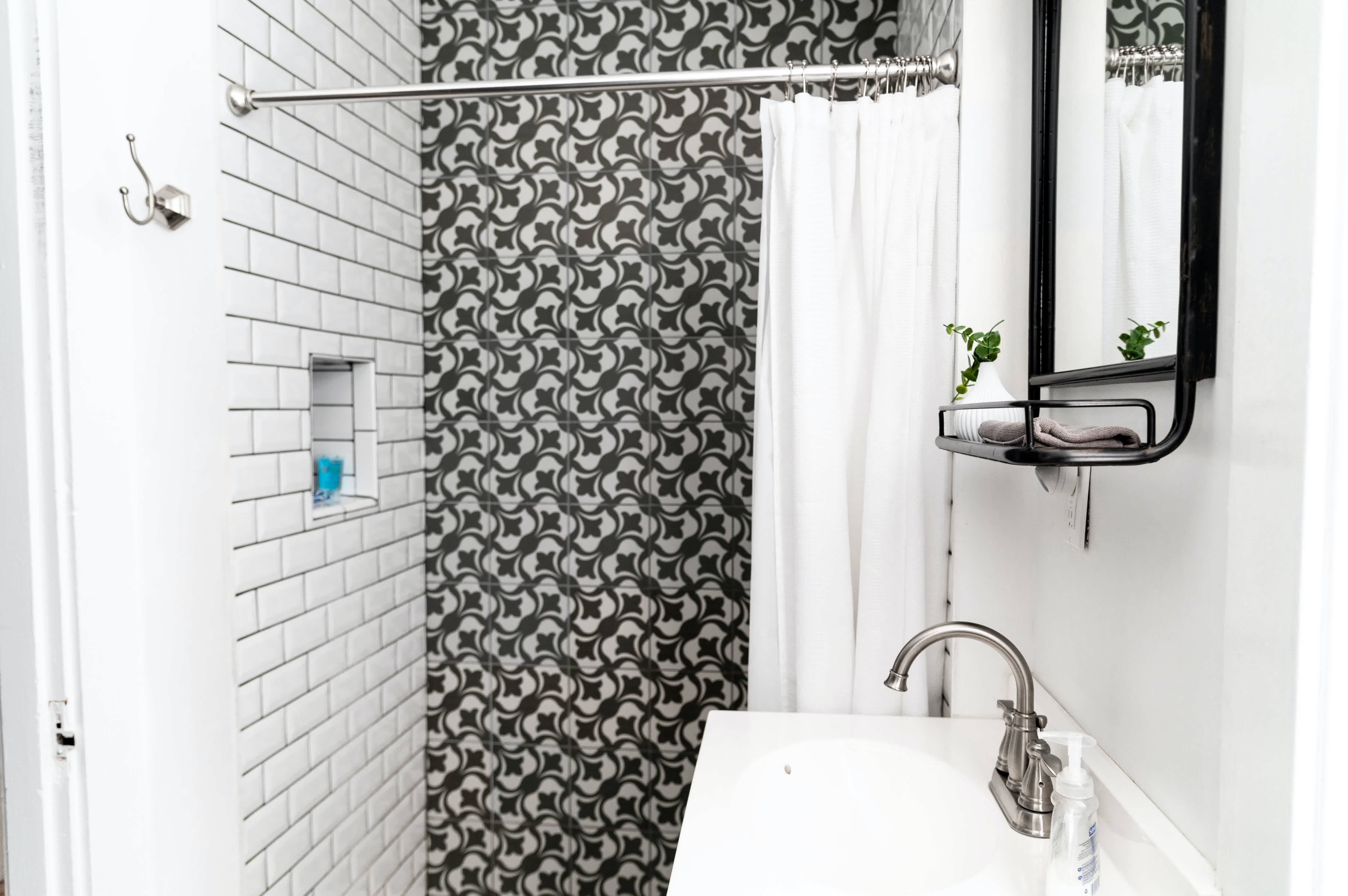 Modern shower with white subway tile wall next black-and-white tile wall