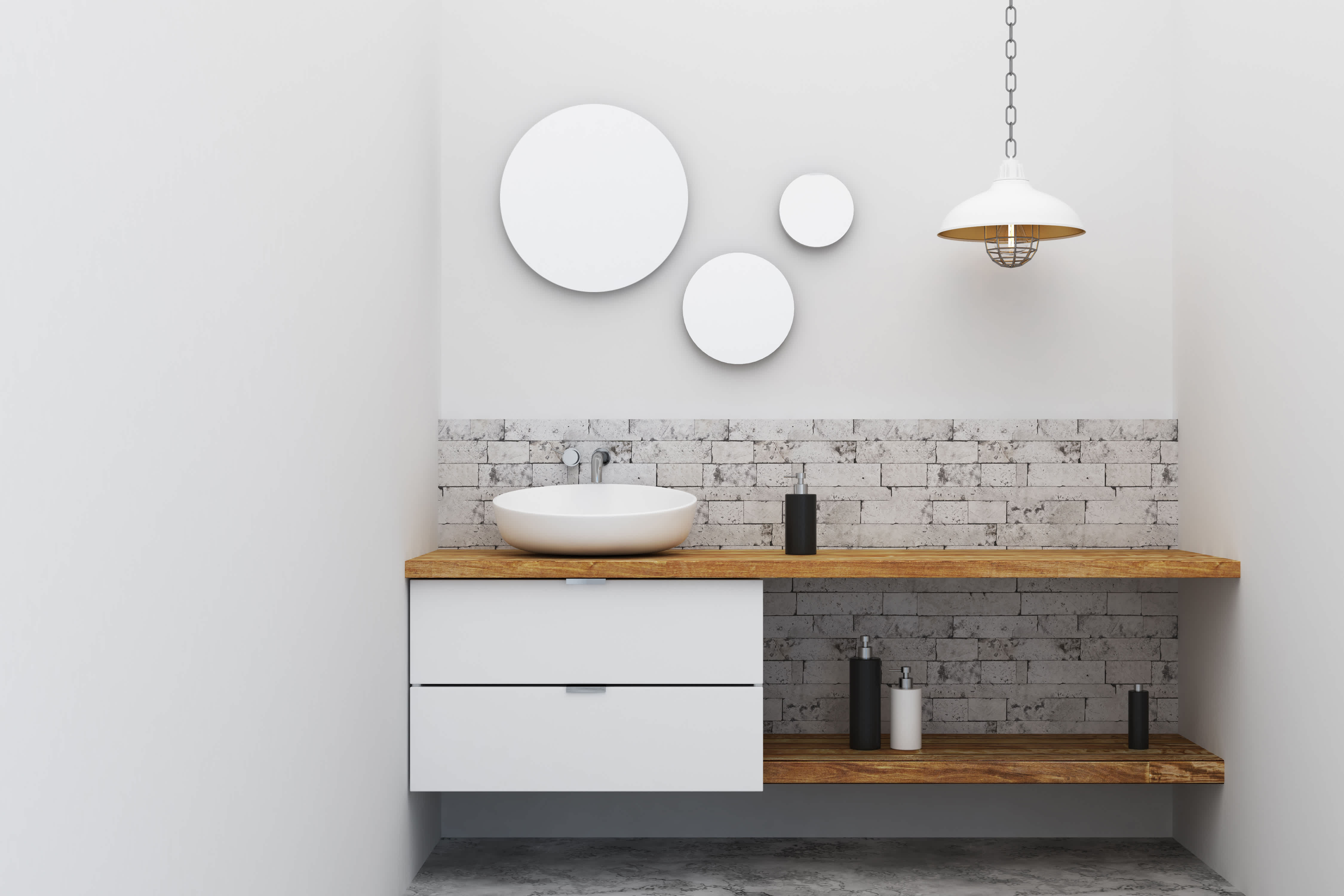Industrial vessel bathroom sink on wood vanity below industrial pendant lamp and three mirrors