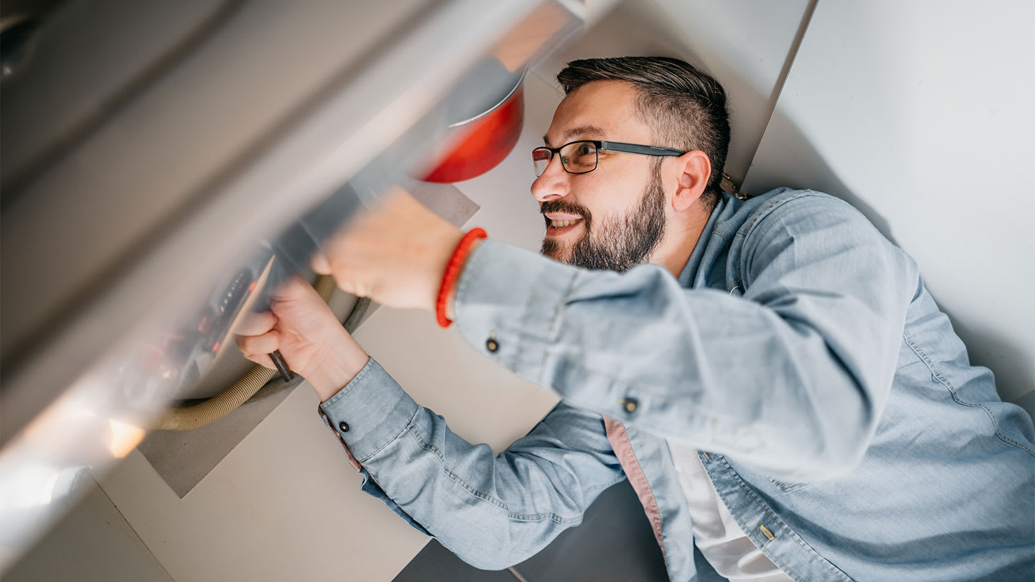 A man looks under a kitchen sink
