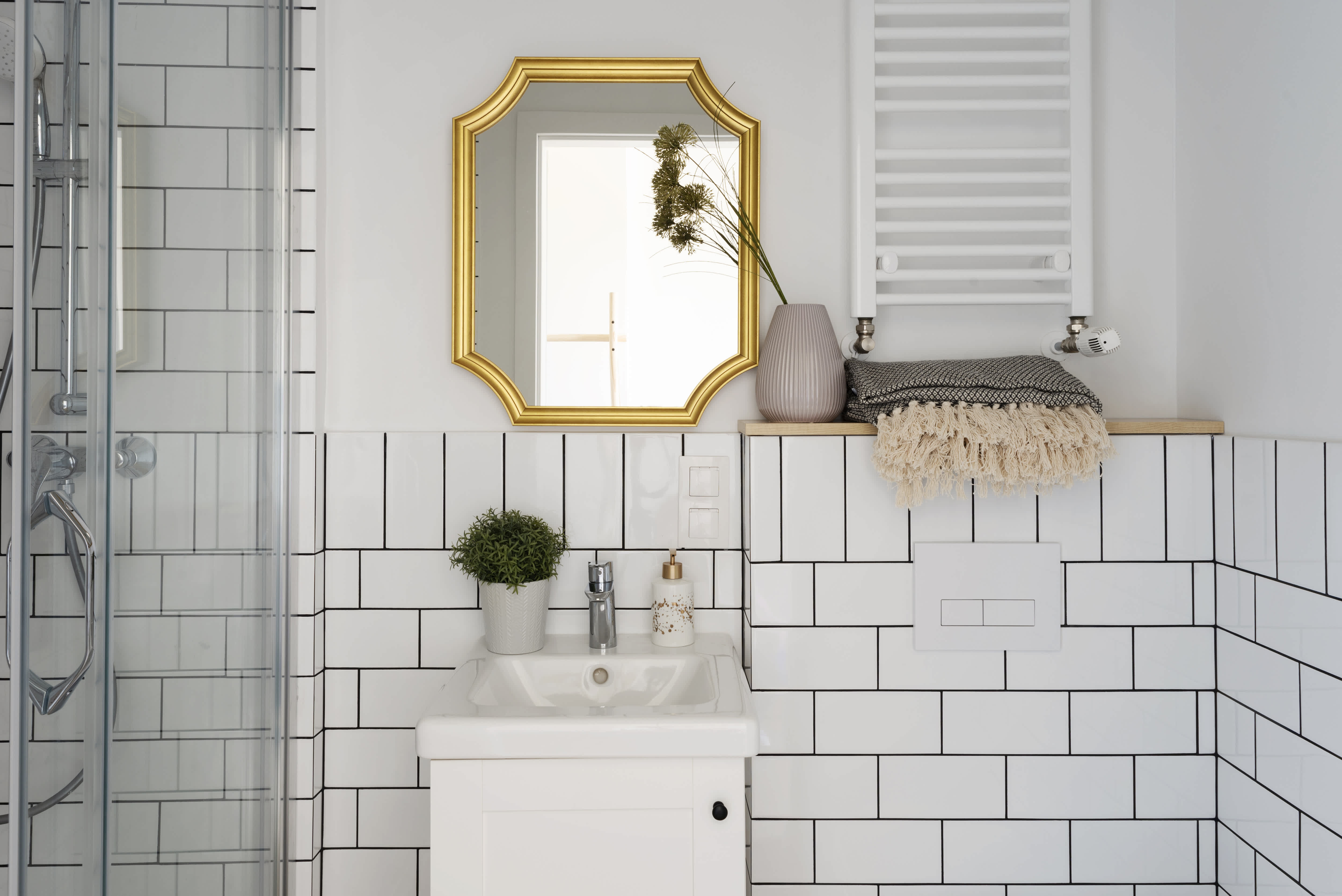 Small bathroom with white subway tiles, bathroom sink and stylish gold mirror on the wall