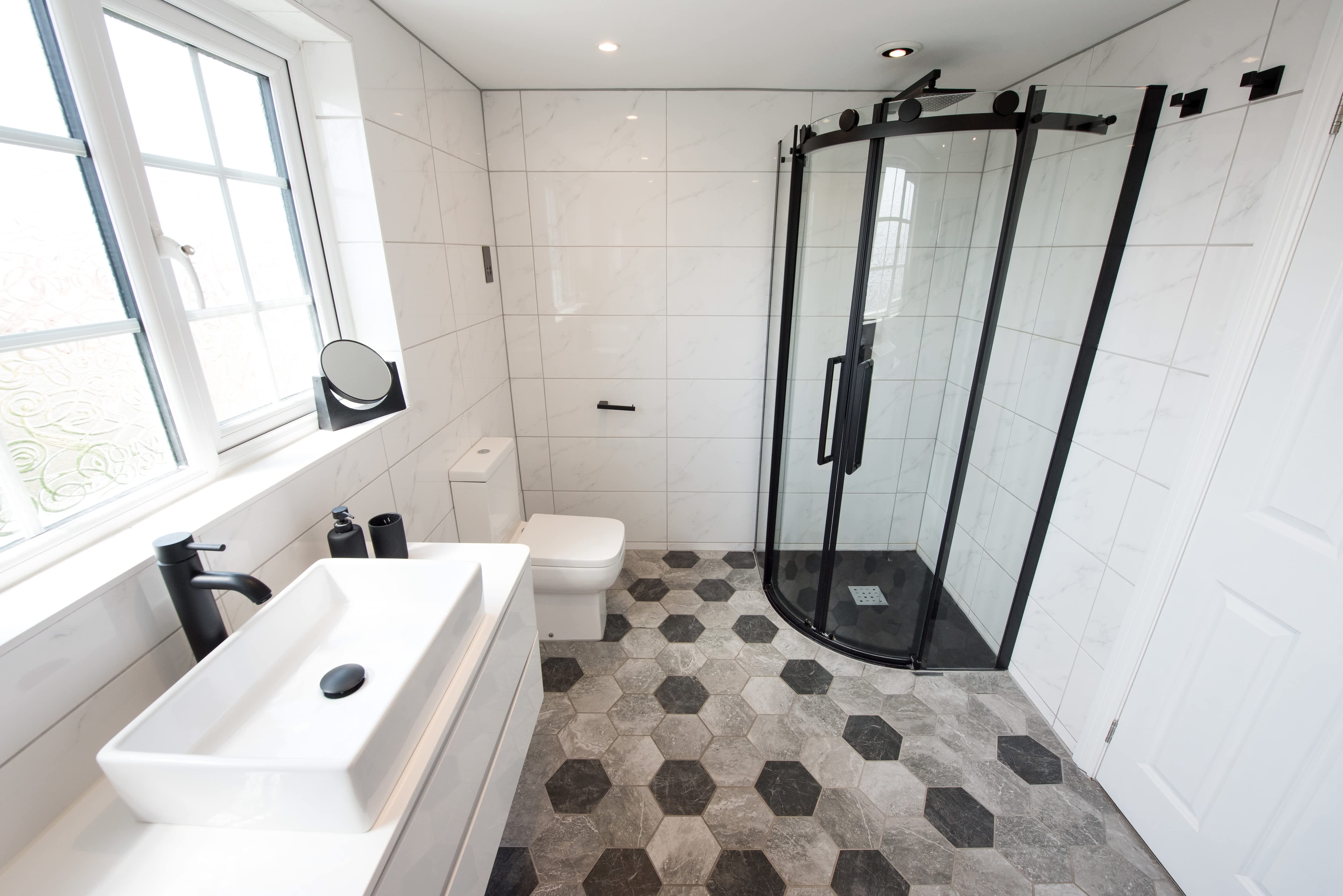 Contemporary bathroom with black-and-gray hexagonal tile floors, a matte black shower cubicle and white wall-hung vanity