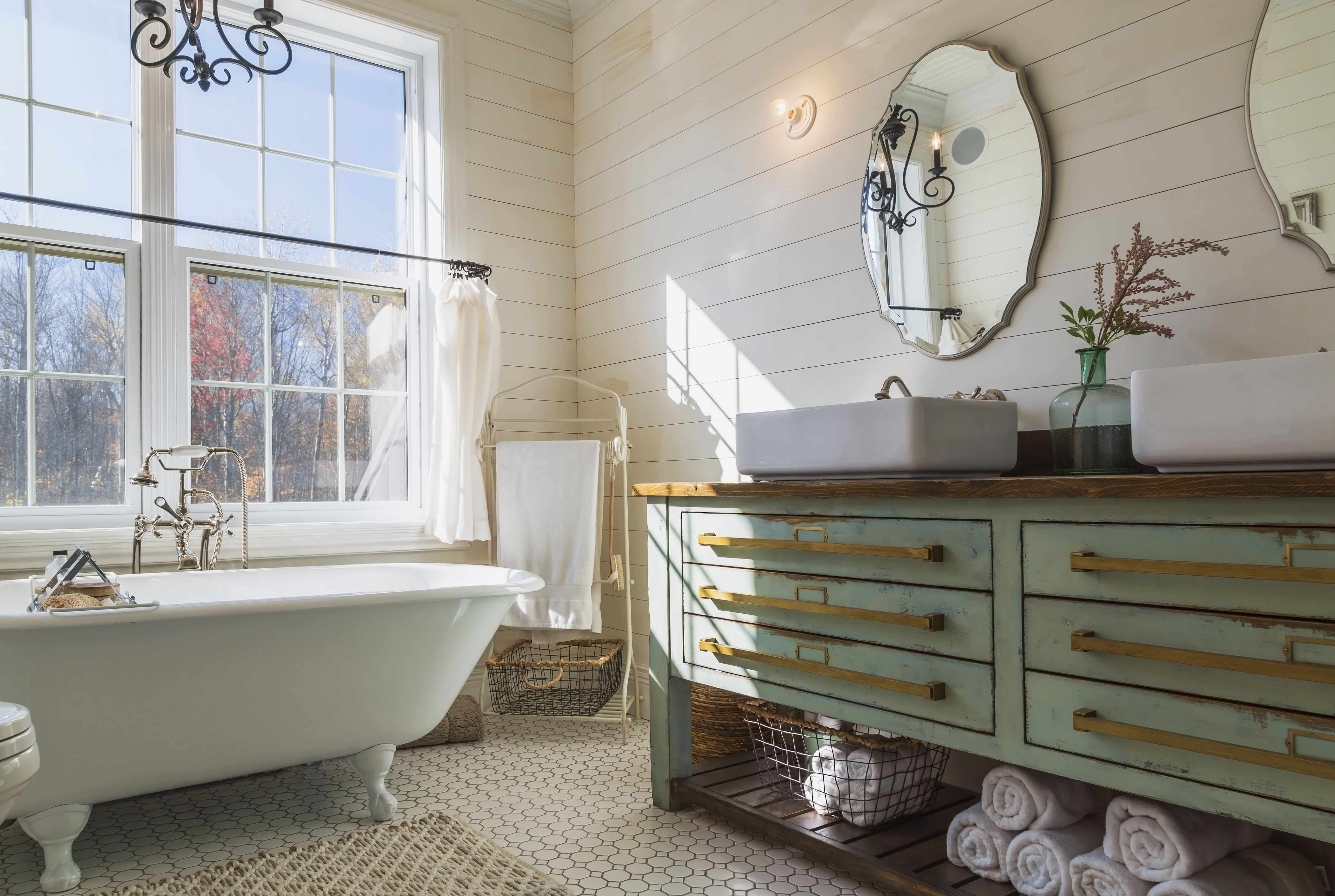 Bathroom with white clawfoot tub, shiplap walls, and mint green vanity unit with double hand basin