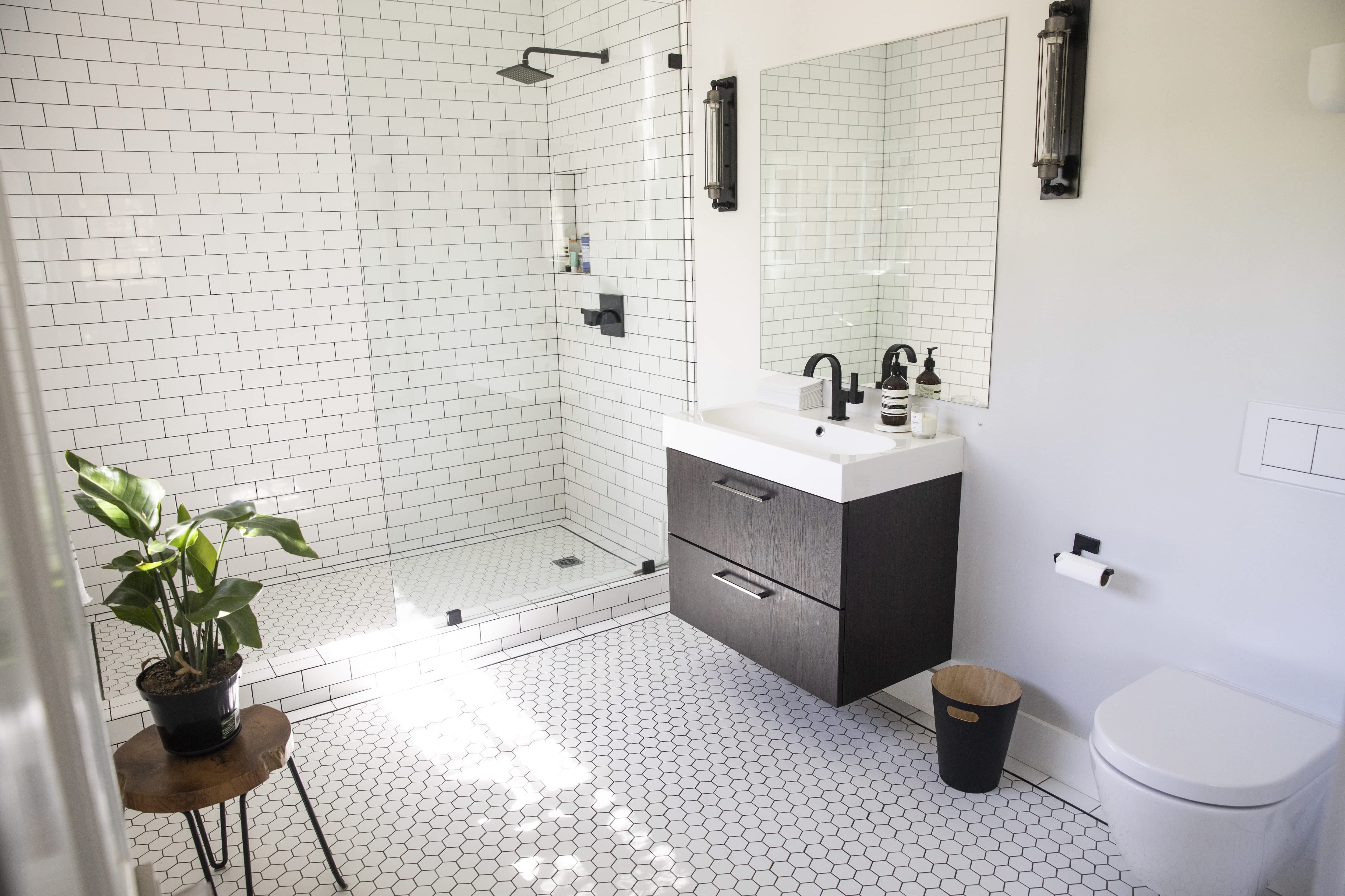 Small luxury bathroom with walk-in shower, white shower subway tile, white hexagonal floor tile, and brown vanity