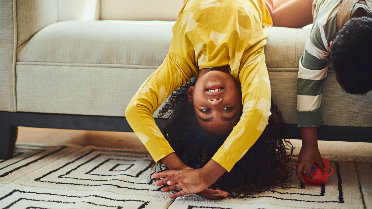 Kids hanging off of couch to touch floor