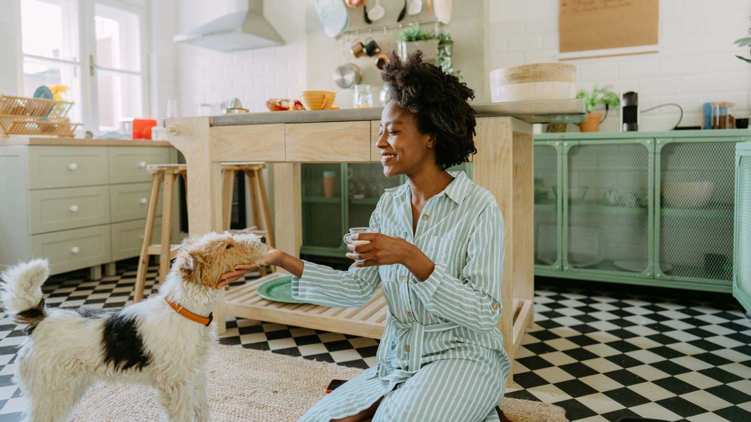 A woman petting her dog on the kitchen floor
