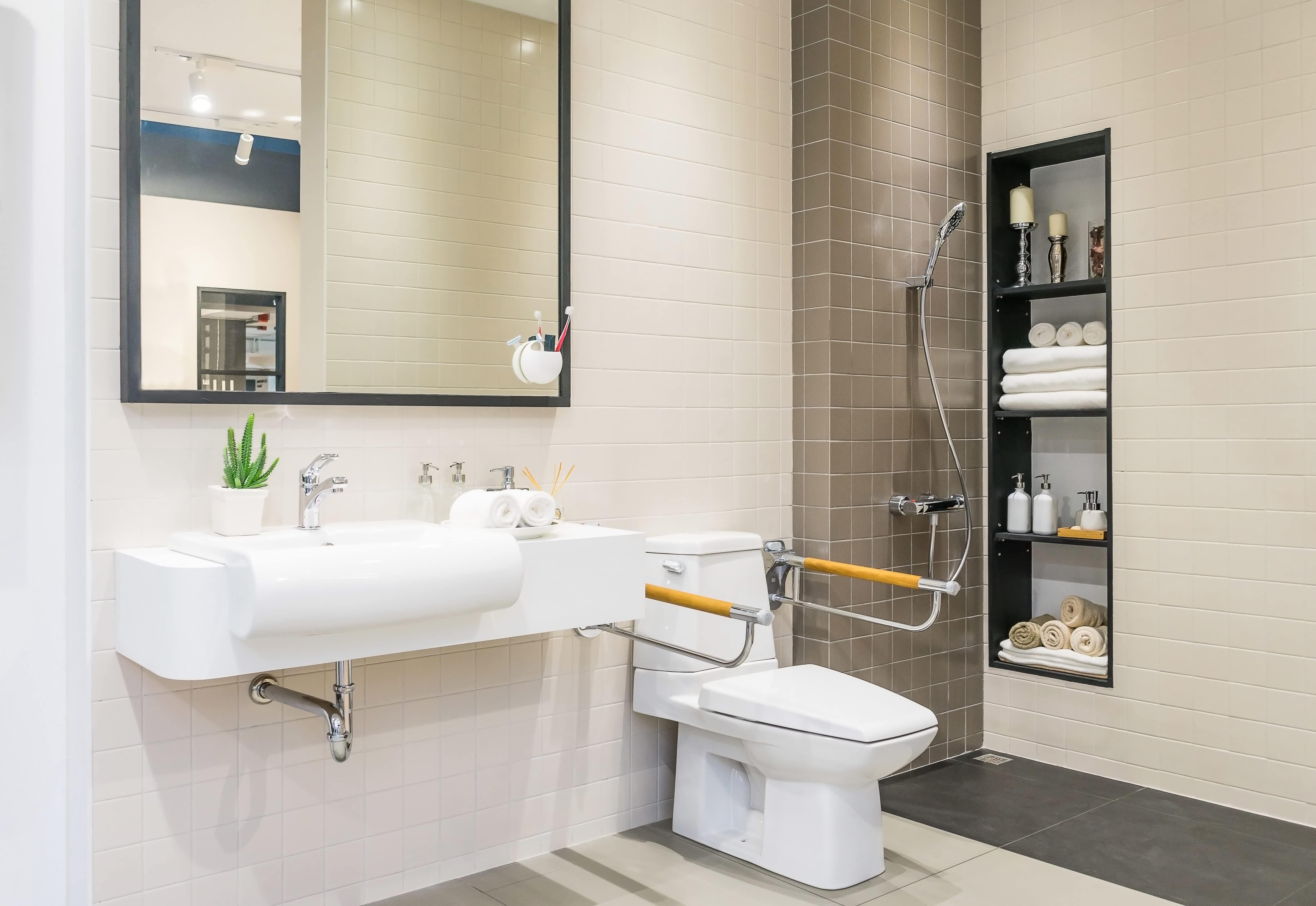 Accessible home bathroom with curbless shower and toilet handrail for people with disabilities