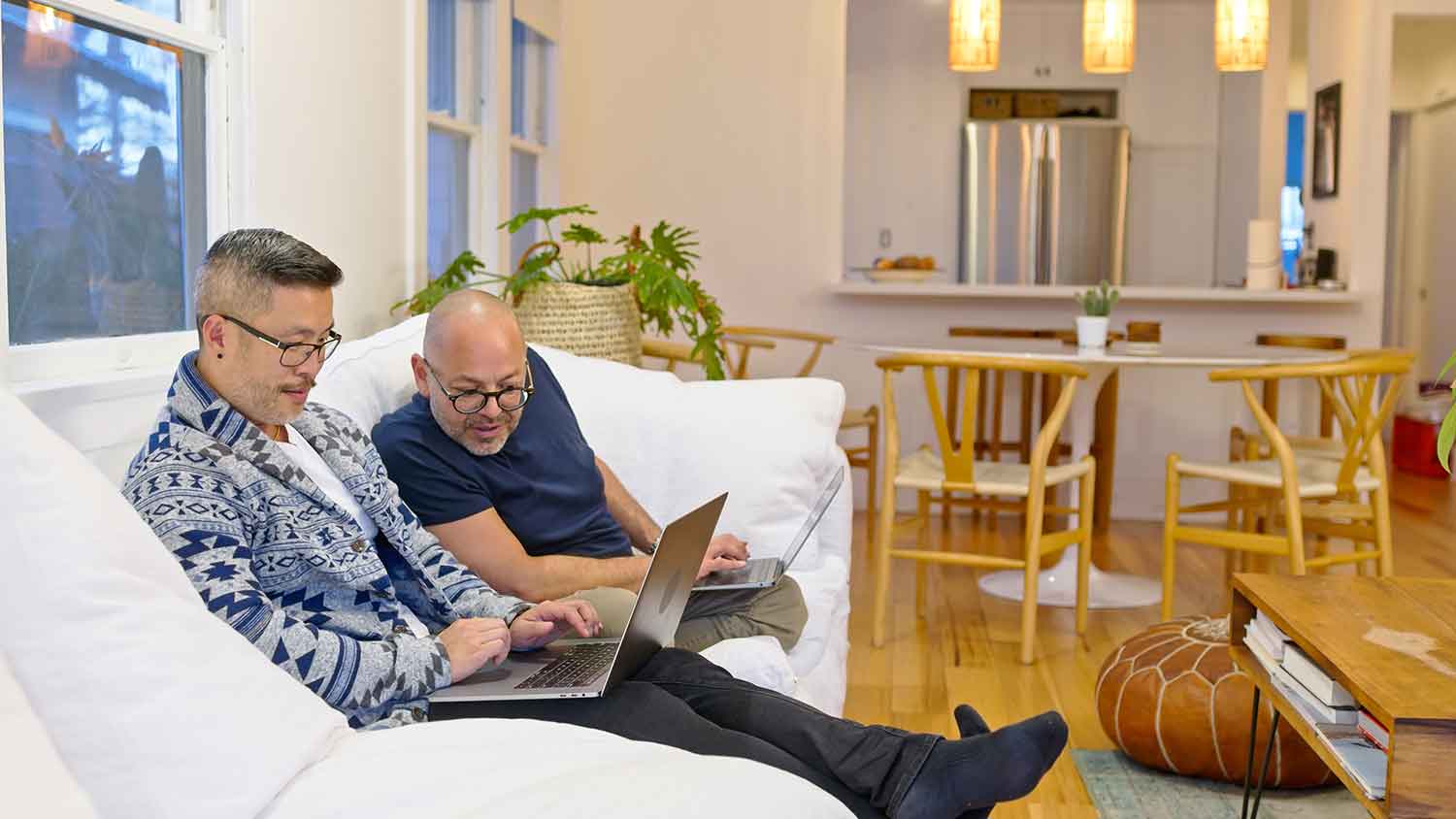 Couple sitting on a sofa using their laptops
