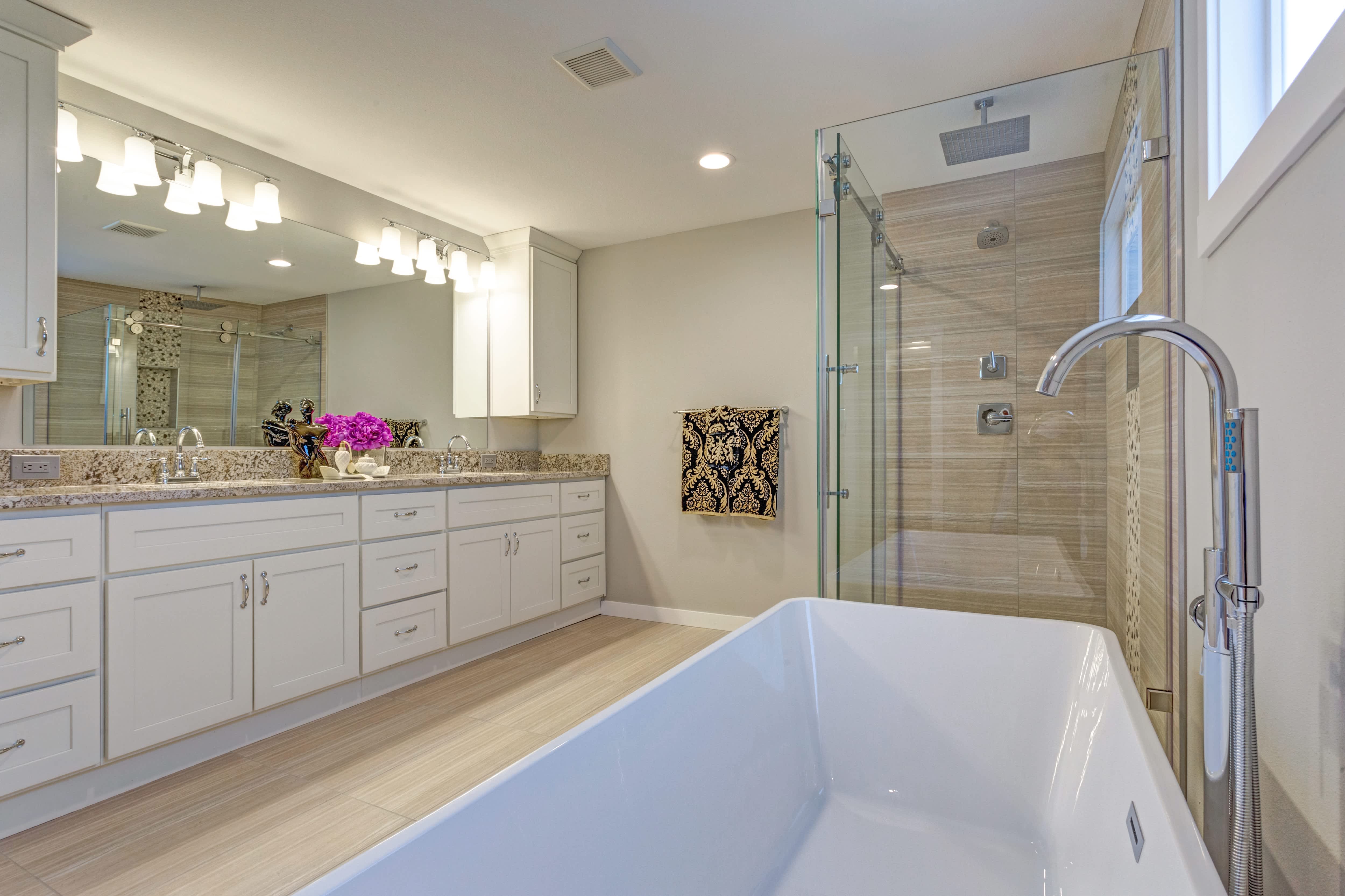 Traditional bathroom design with long white vanity cabinet, standup shower, and freestanding tub