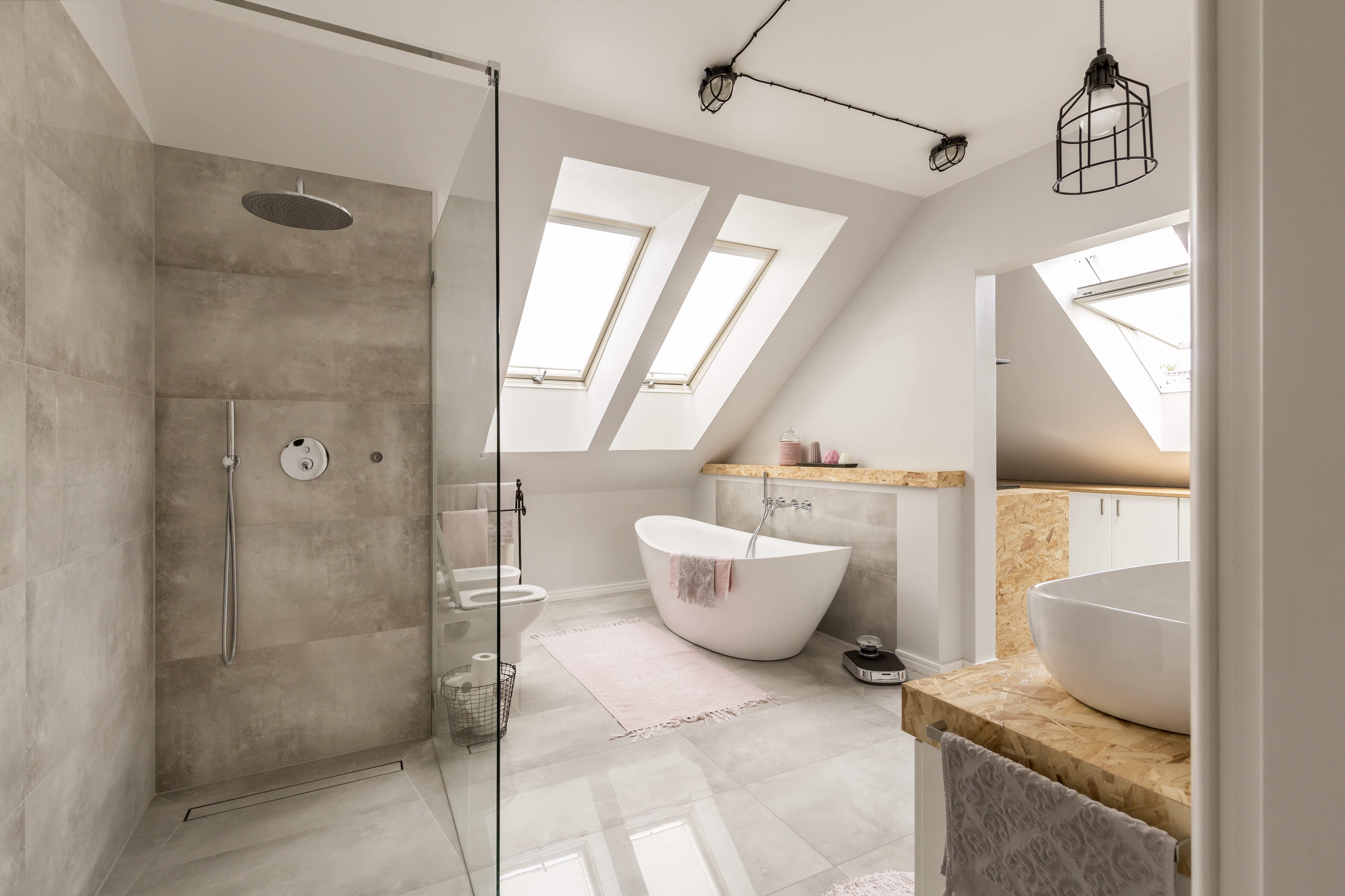 Luxury minimalist bathroom with gray tiled walk-in shower, free-standing white tub, and gray and tan vanity
