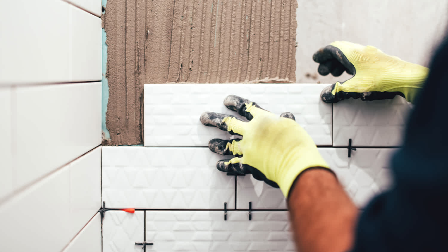 A worker installing bathroom tiles and grout