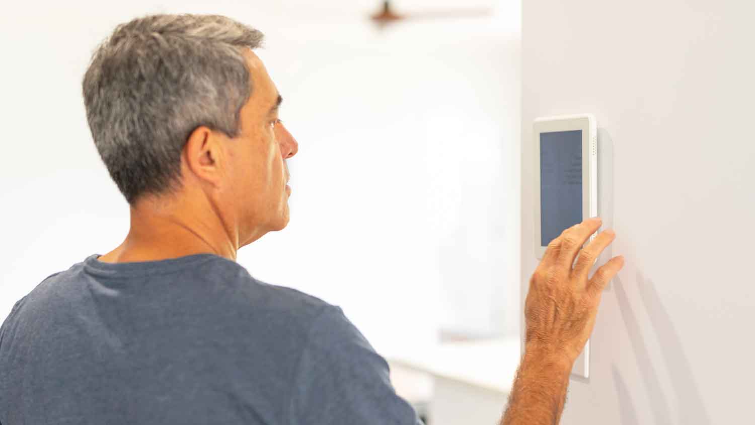Man at home adjusting digital thermostat settings