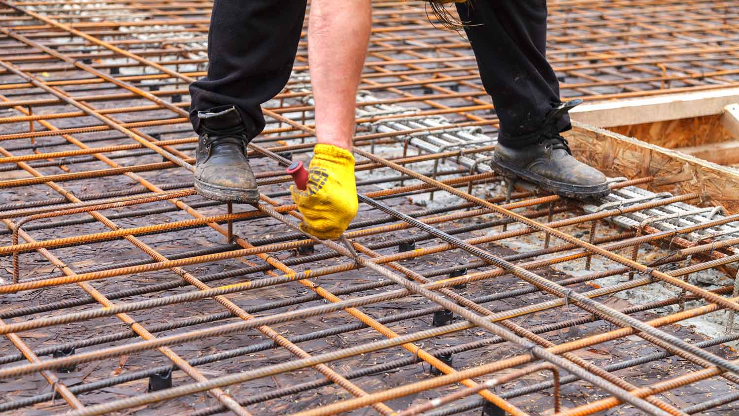 A worker reinforcing steel bars with wire