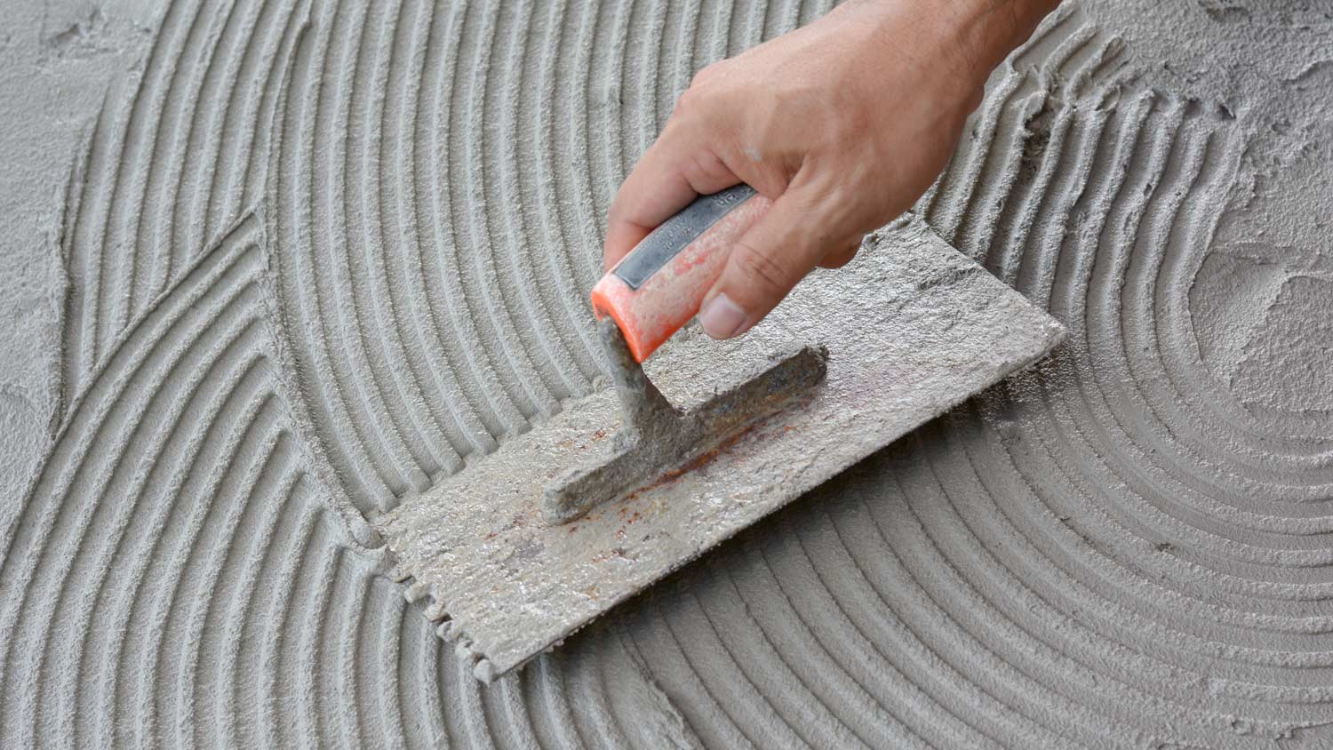 A hand applying cement to a surface