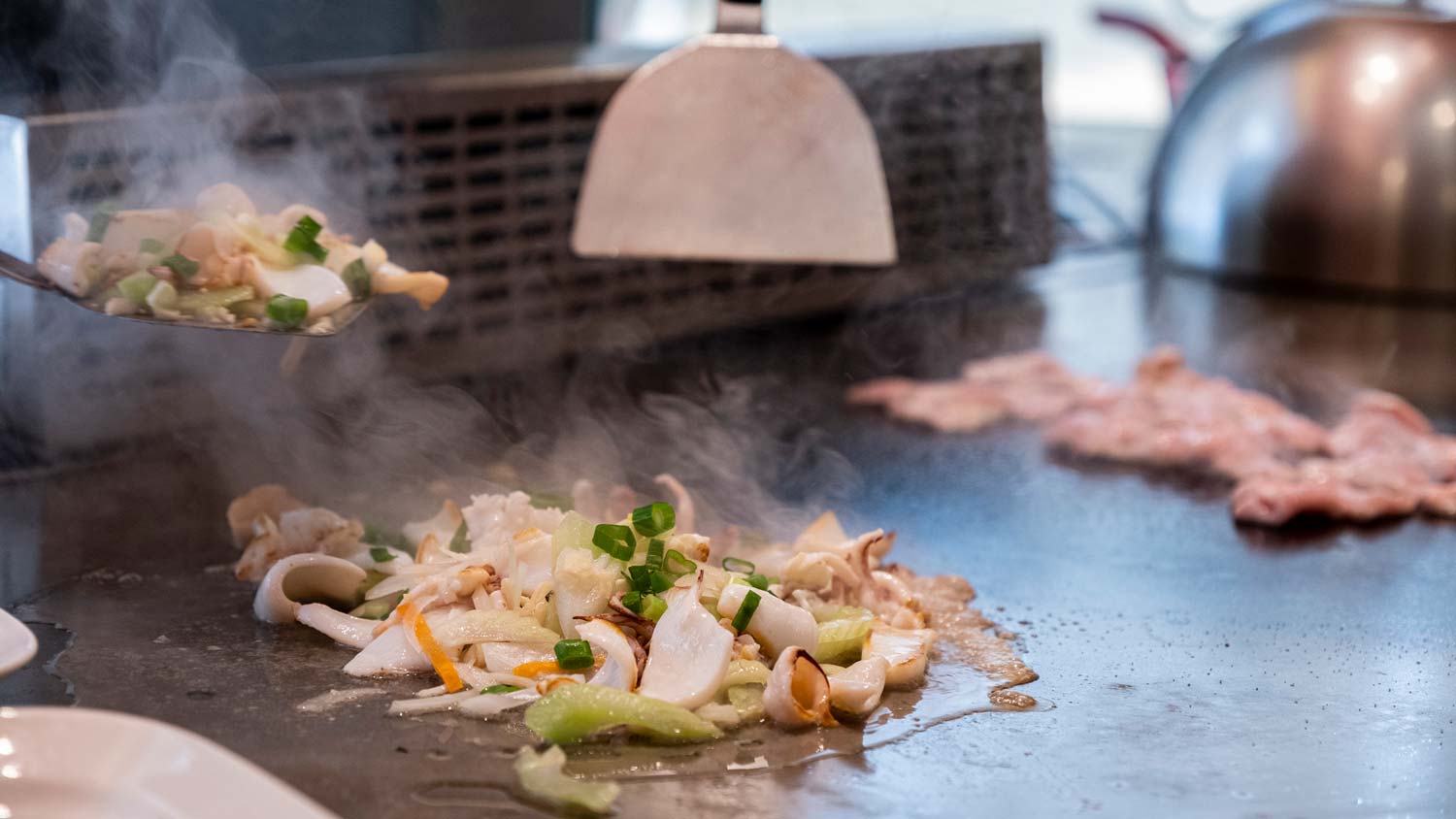 Vegetables and seafood being cooked on griddle