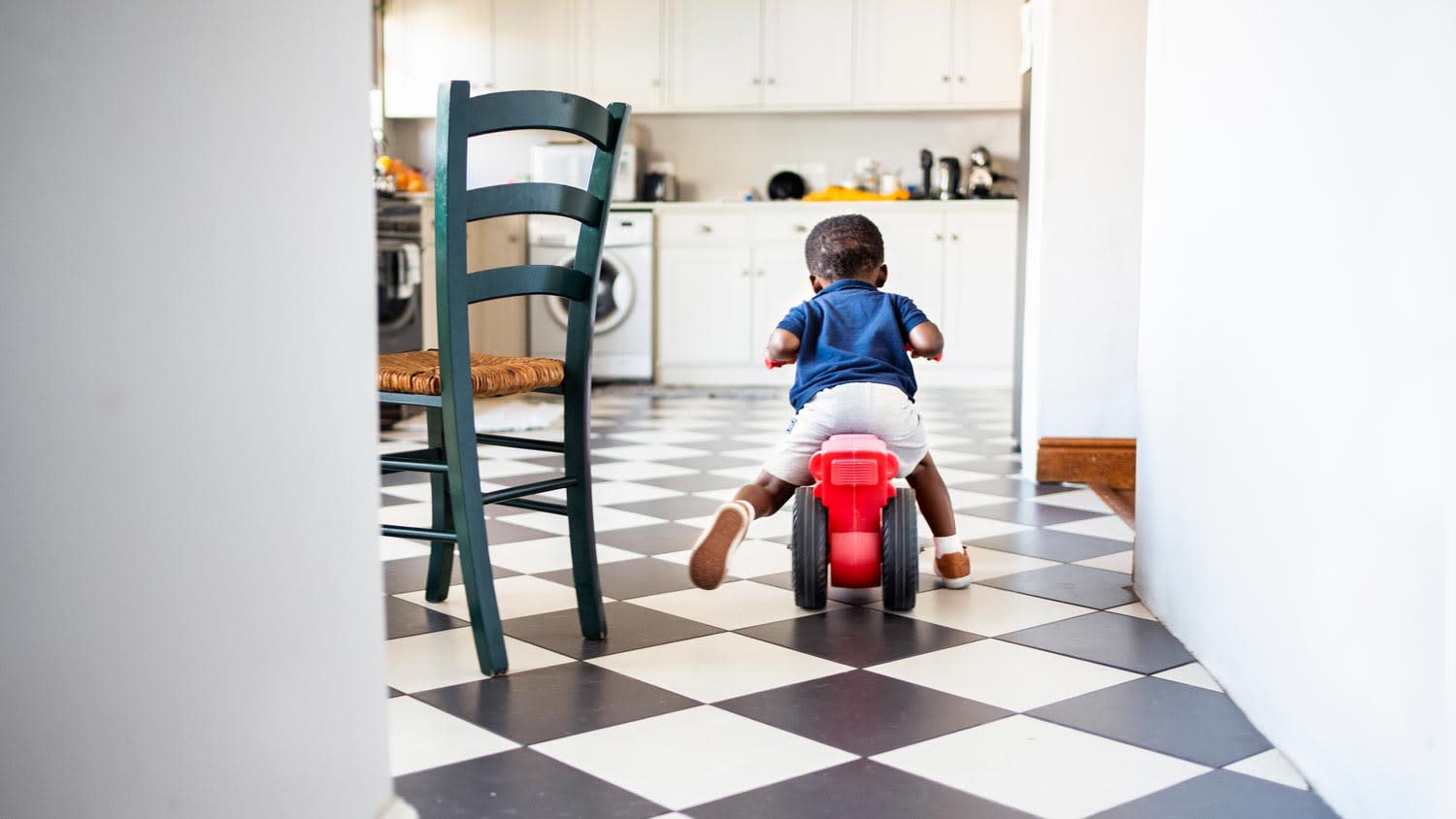 child riding around on bike in tile kitchen