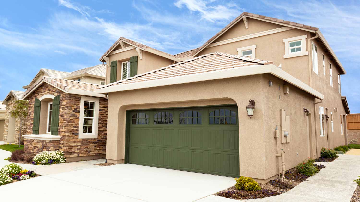 The exterior of a house in the suburbs with a dark green garage door