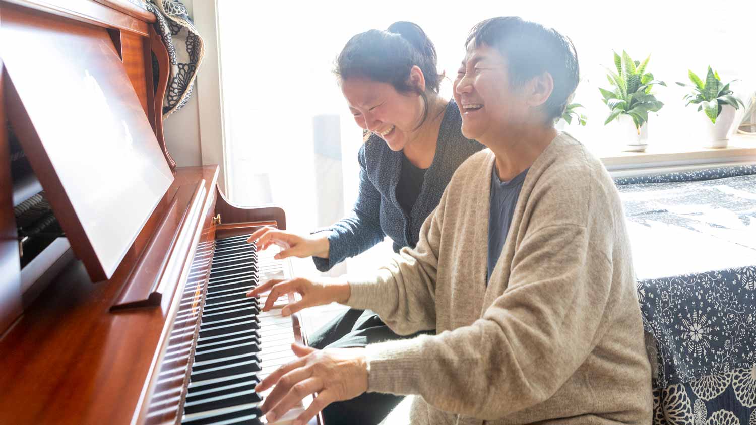 A mother and her daughter playing the piano
