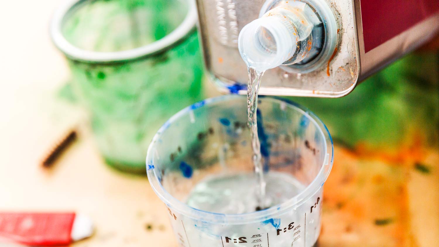 Mineral spirits pouring into paint measuring cup