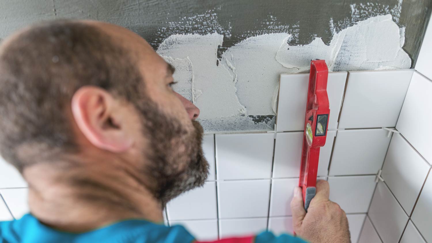 man measuring bathroom tiles on wall