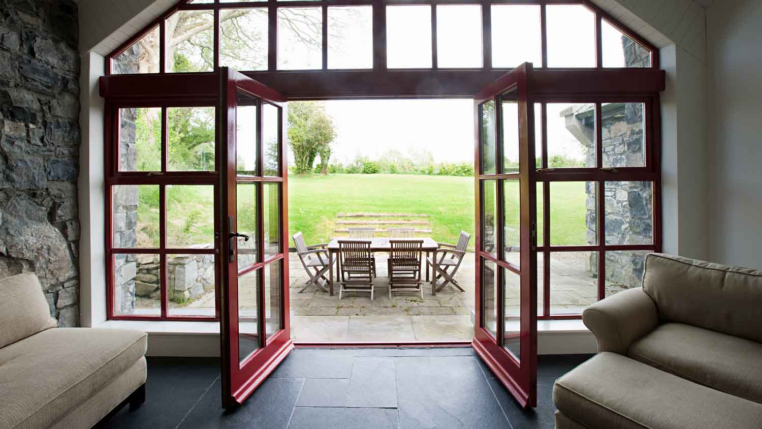 A room with slate tiles and open doors leading to a patio
