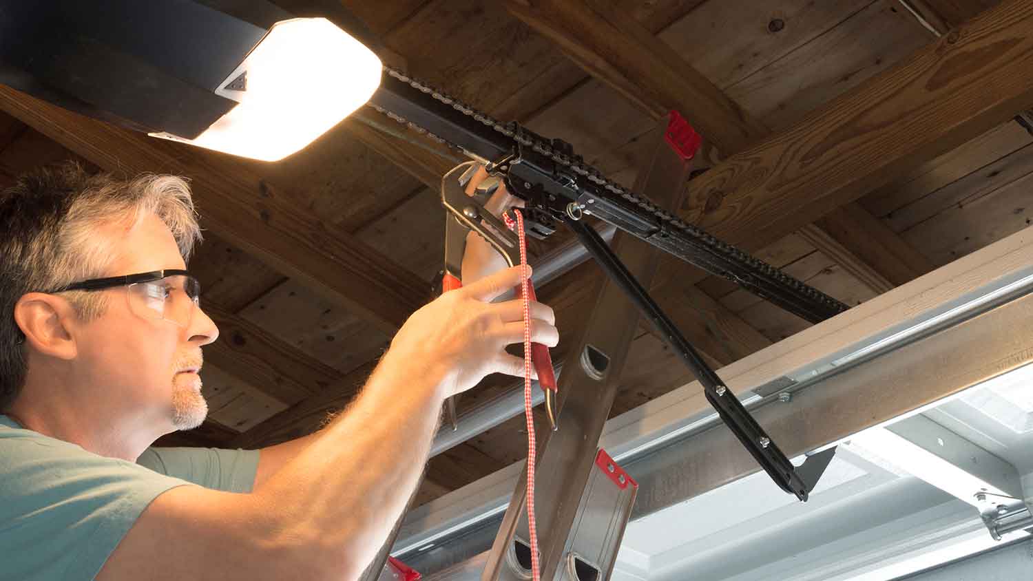 Technician on a ladder tightening automatic garage door chain