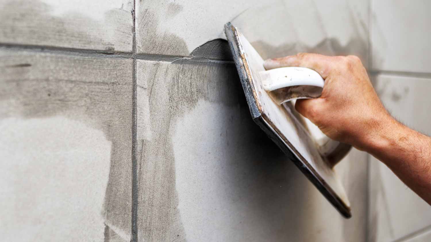 Worker filling the space between tiles